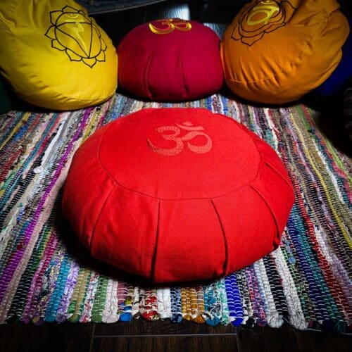 Red meditation cushion with om sanskrit symbol on colorful rug for sale at the om shoppe in sarasota fl