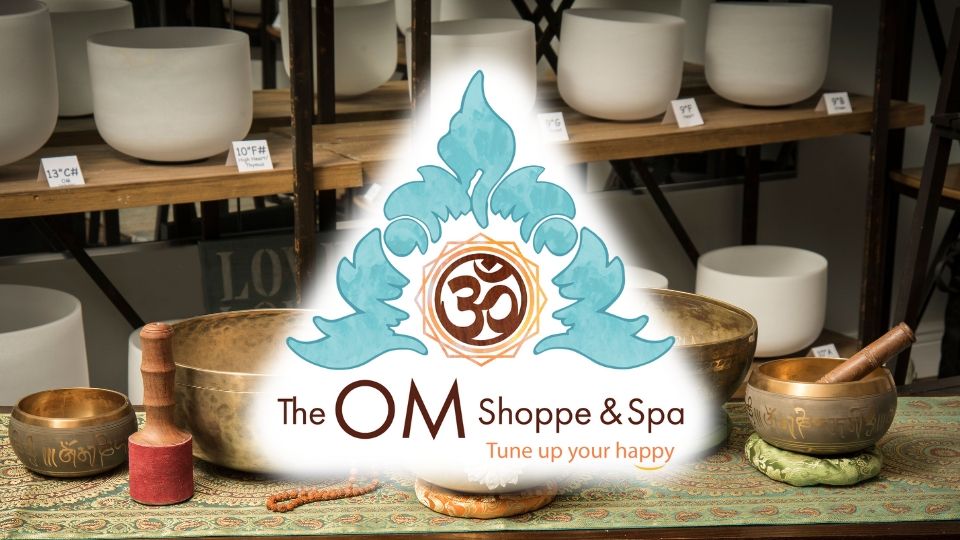 The Om Shoppe logo over a shelf full of frosted singing bowls