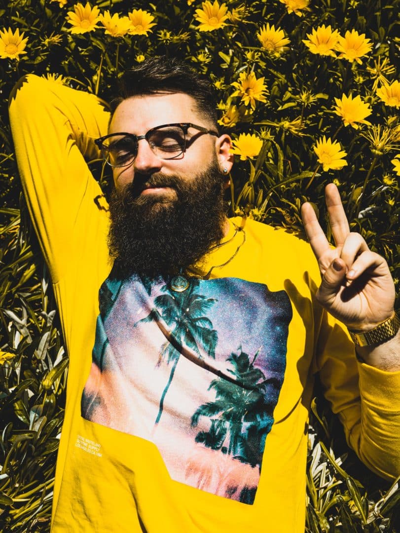 man lying in sunflower with peace sign