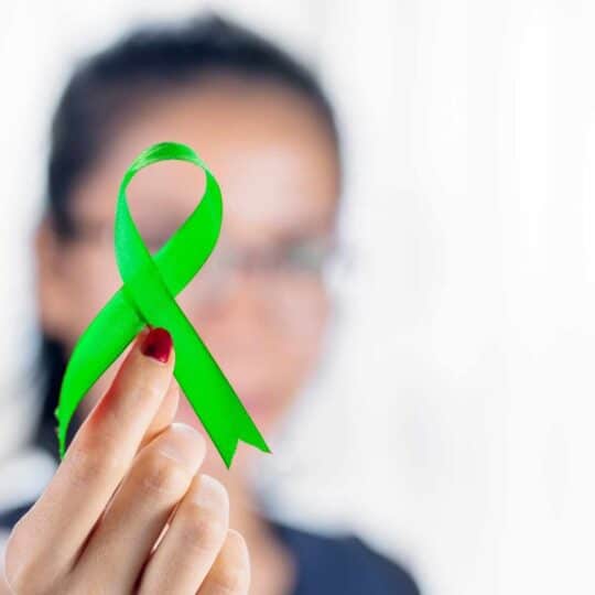 woman holding a green ribbon for mental health awareness month